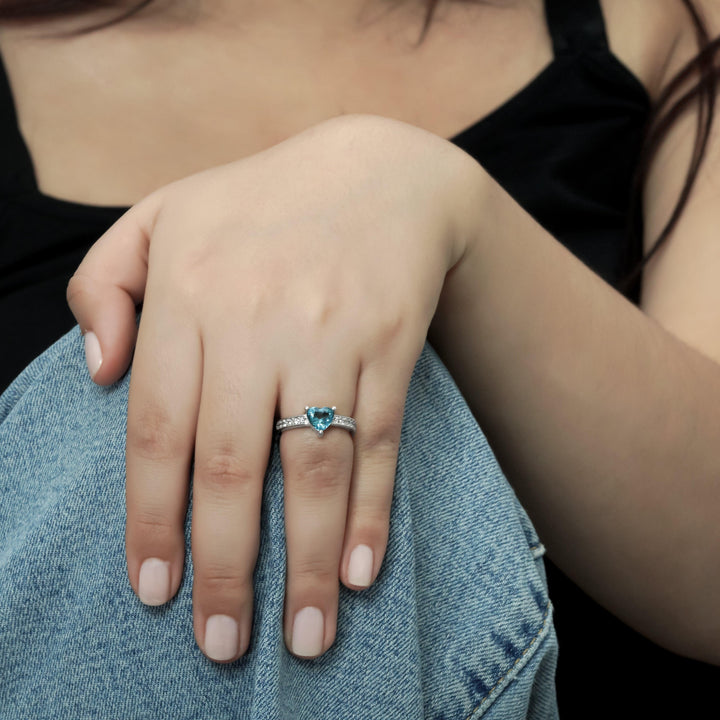 Woman wearing a blue topaz and diamond ring in sterling silver posing with hand on knee CHC Fine Jewelry